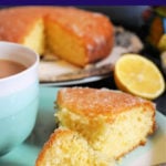 A slice of lemon drizzle cake on a light blue plate with half a lemon and more cake in the background