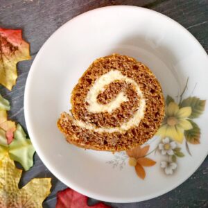 A slice of pumpkin roll on a white dessert plate