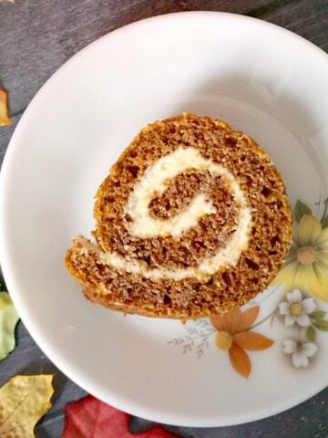 A slice of pumpkin roll on a white dessert plate