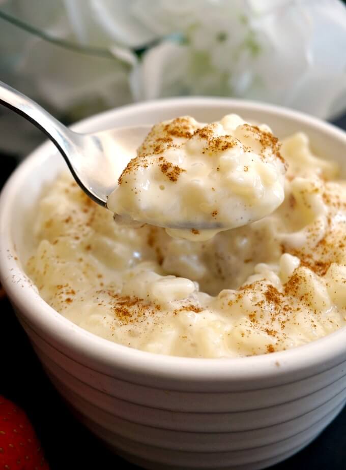 A rameskin of rice pudding with a teaspoon scooping pudding