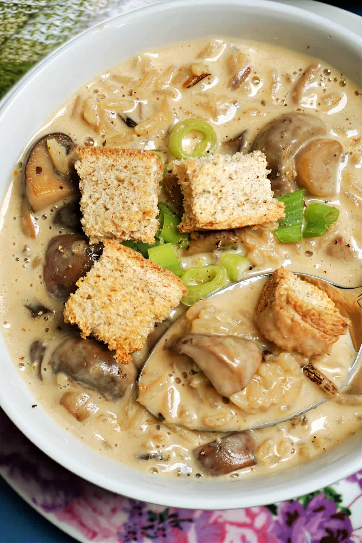 A white bowl of mushroom, rice and croutons soup.