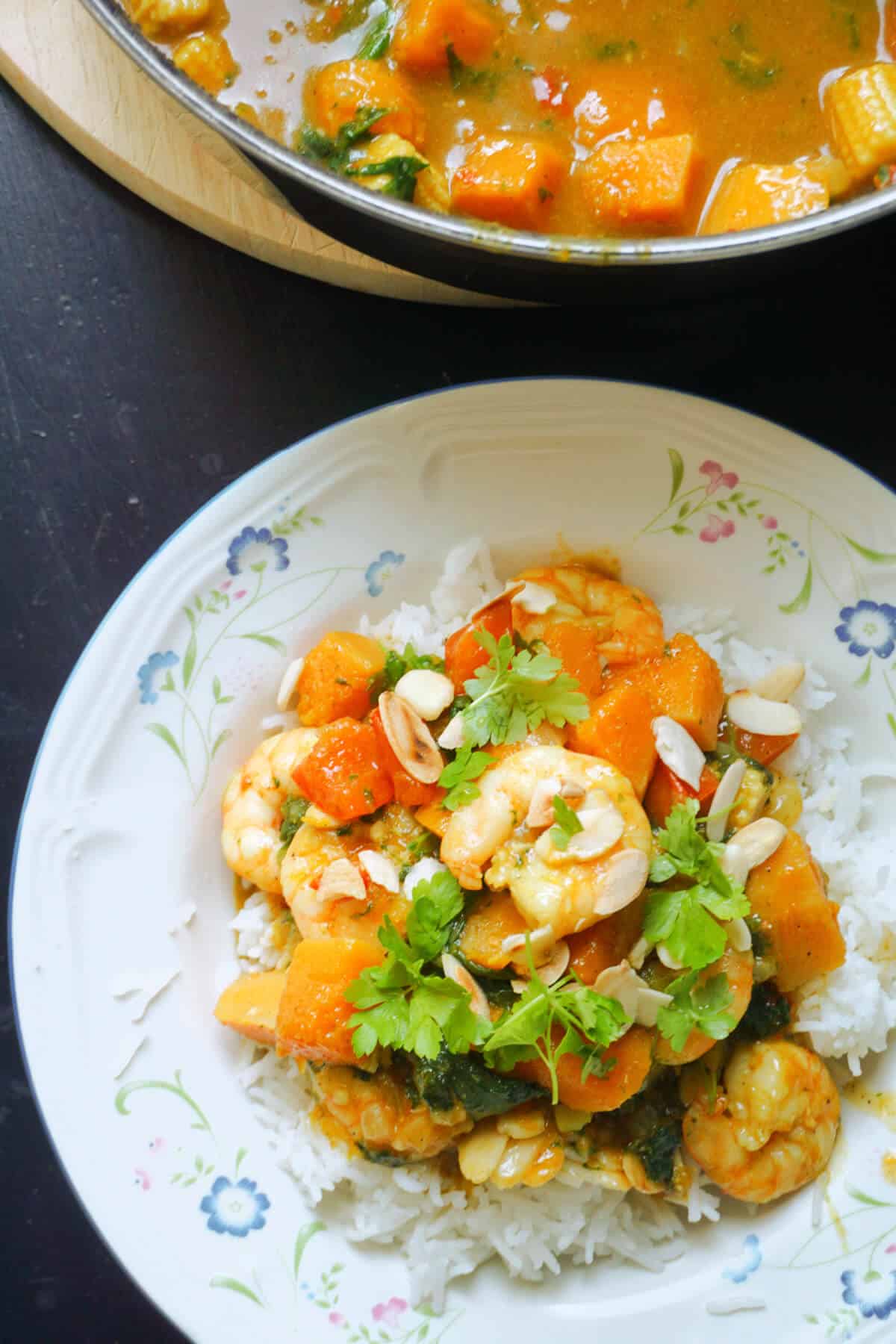 Overhead shoot of a white plate with prawn and veggies over a bed of rice.