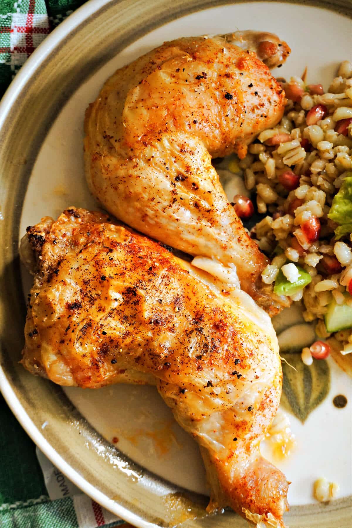 2 baked chicken legs on a plate with a salad on the side.