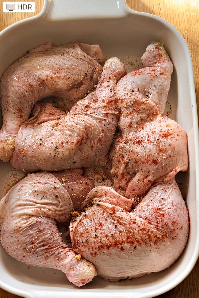 A pan with 5 seasoned chicken legs ready for baking.