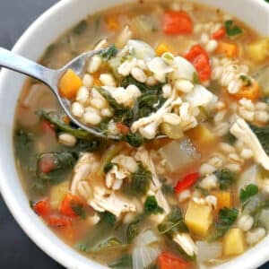 A white bowl with chicken and barley soup