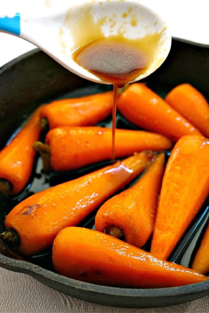 A skillet with baby carrots with a glazed being poured over them