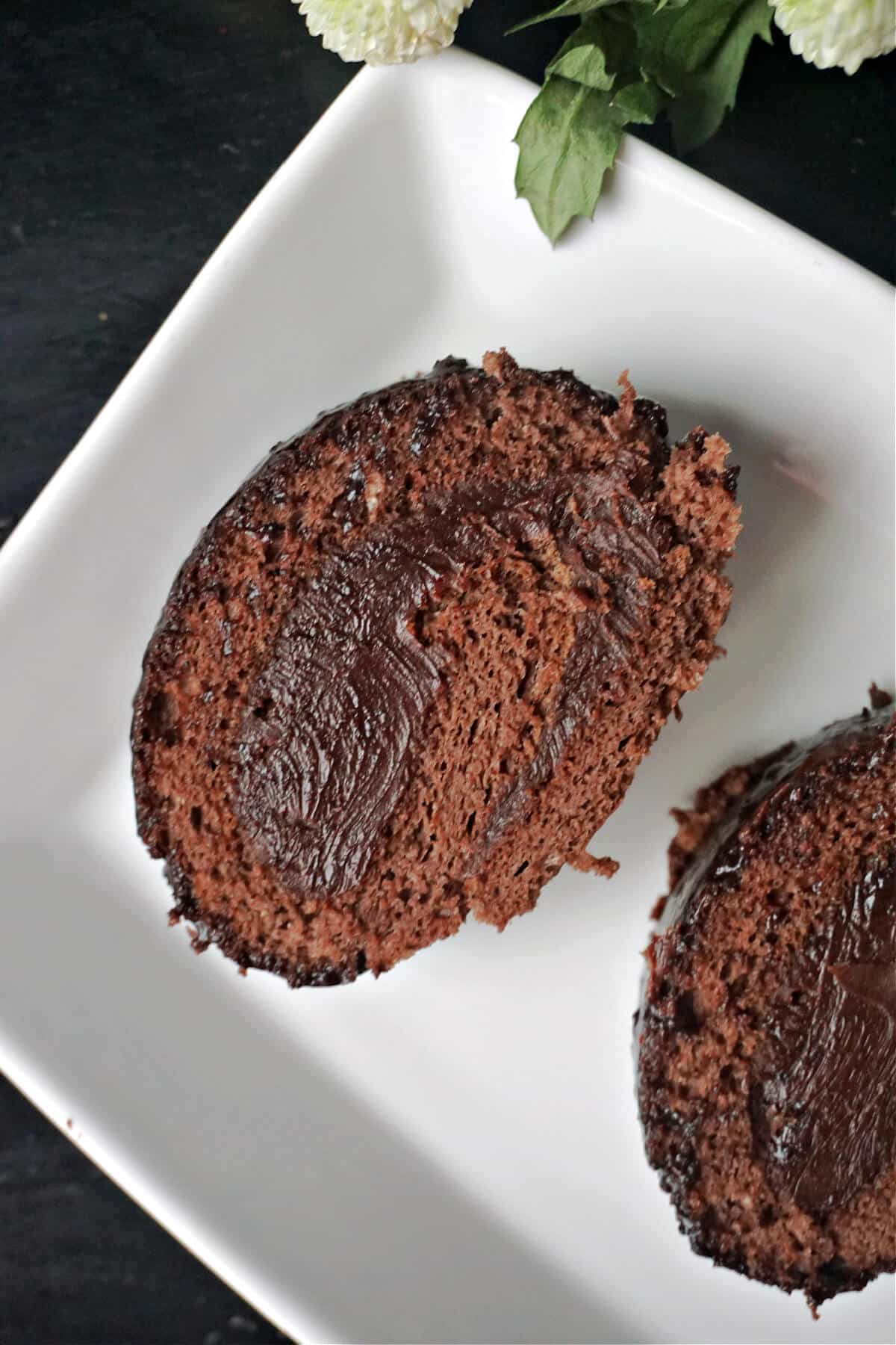 A white plate with 2 slices of chocolate cake roll.