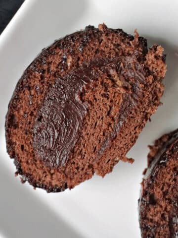 A white plate with a slice of chocolate swiss roll.