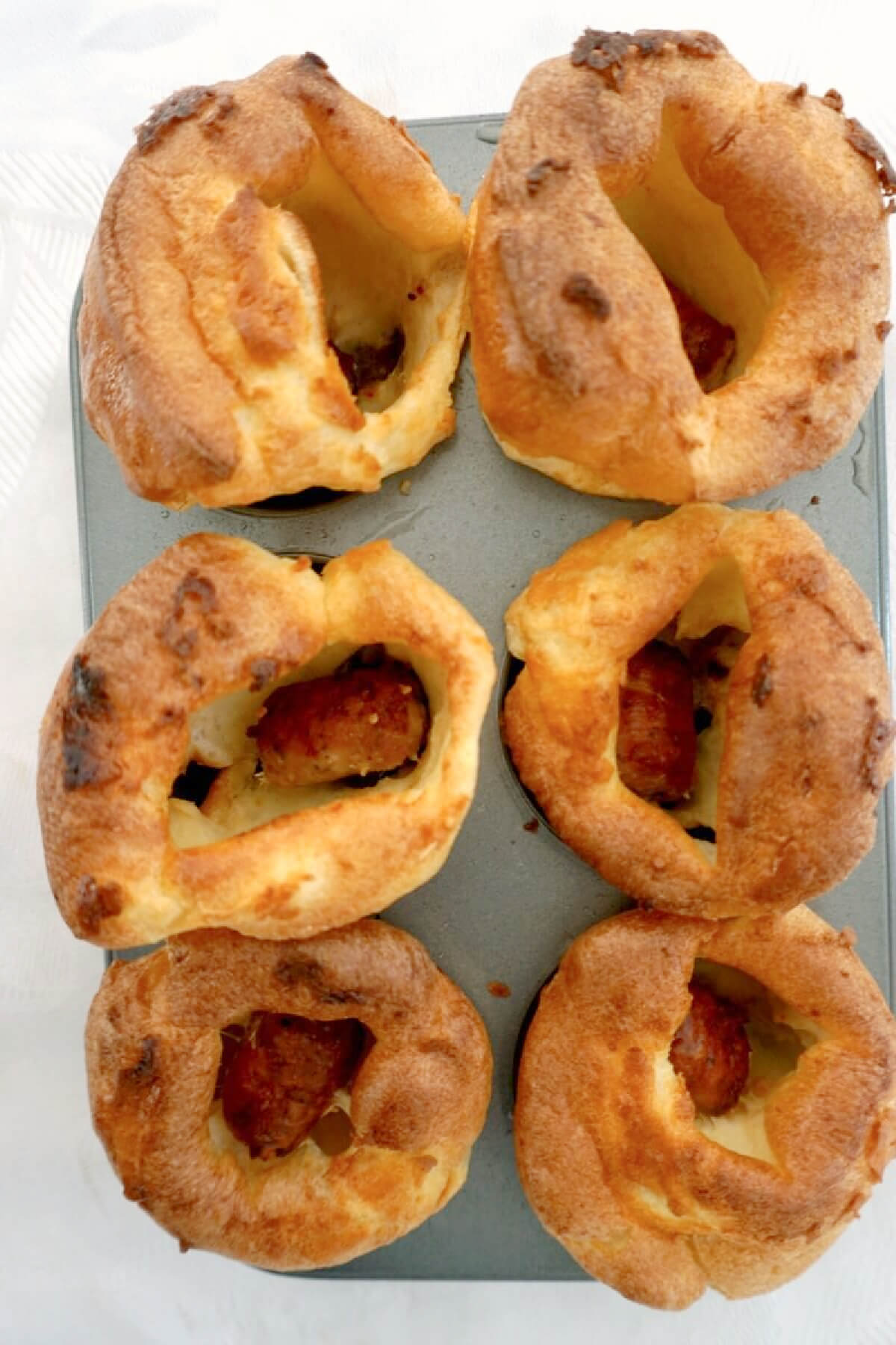 Overhead shoot of a 6-hole muffin tin with mini toad in the hole.