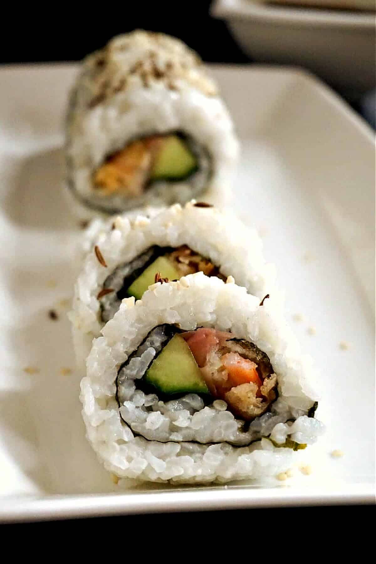 3 sushi rolls on a white plate.