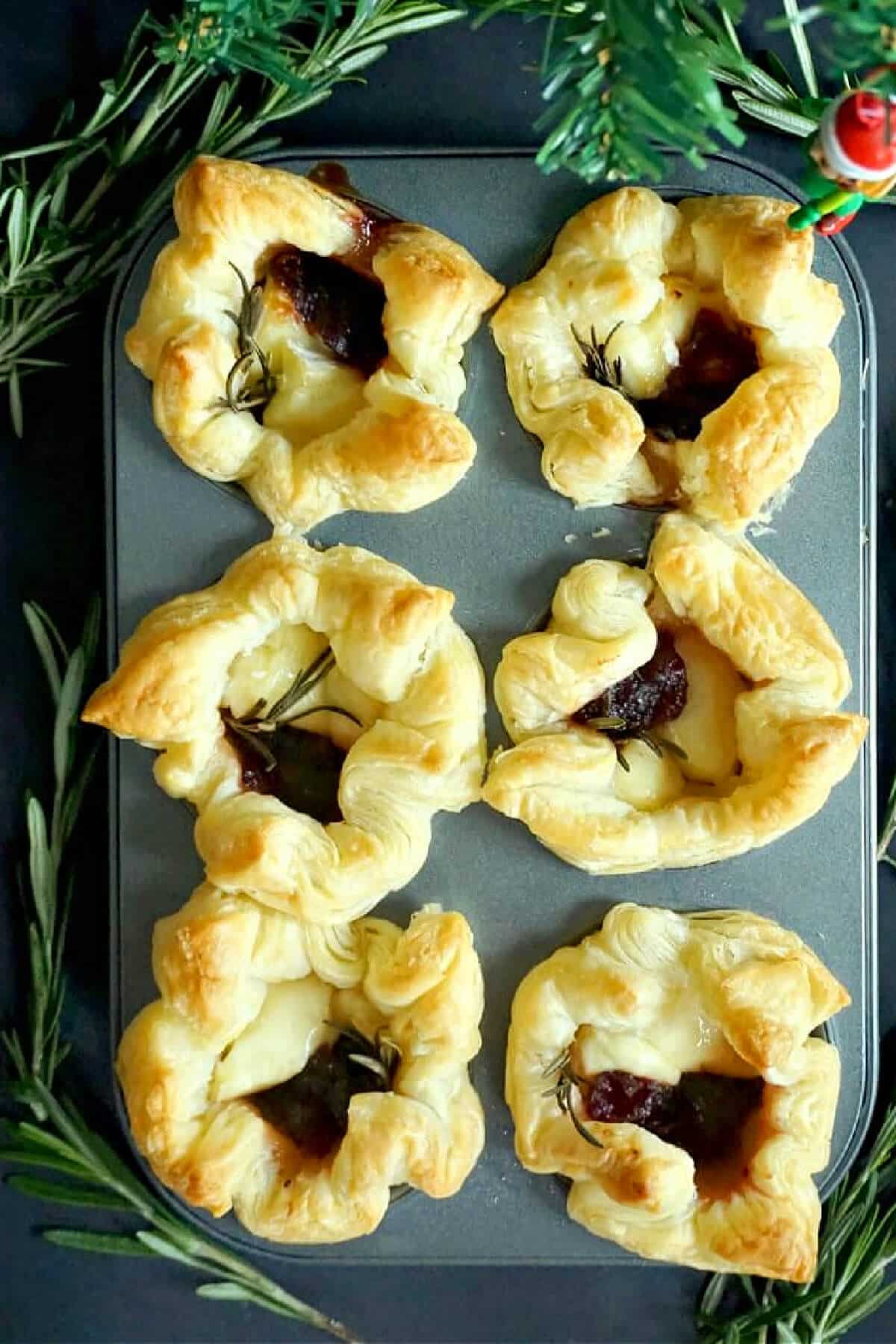 Overhead shoot of a muffin tin with 6 cranberry and brie puffs.