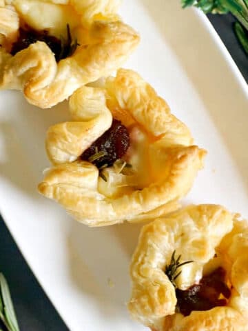 Overhead shoot of 3 brie and cranberry bites on a white rectangle plate