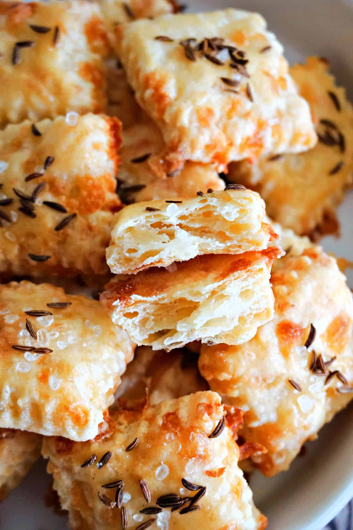 Close-up of 2 halves of a cheese cracker sitting on top of other whole crackers.