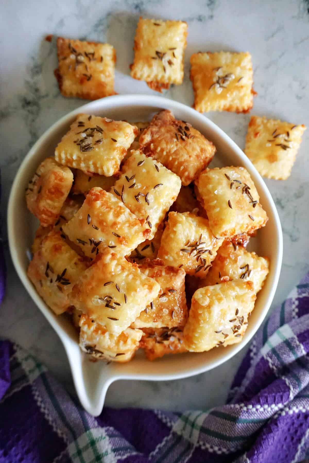 A white serving bowl with cheese bites and more bites around the bowl.
