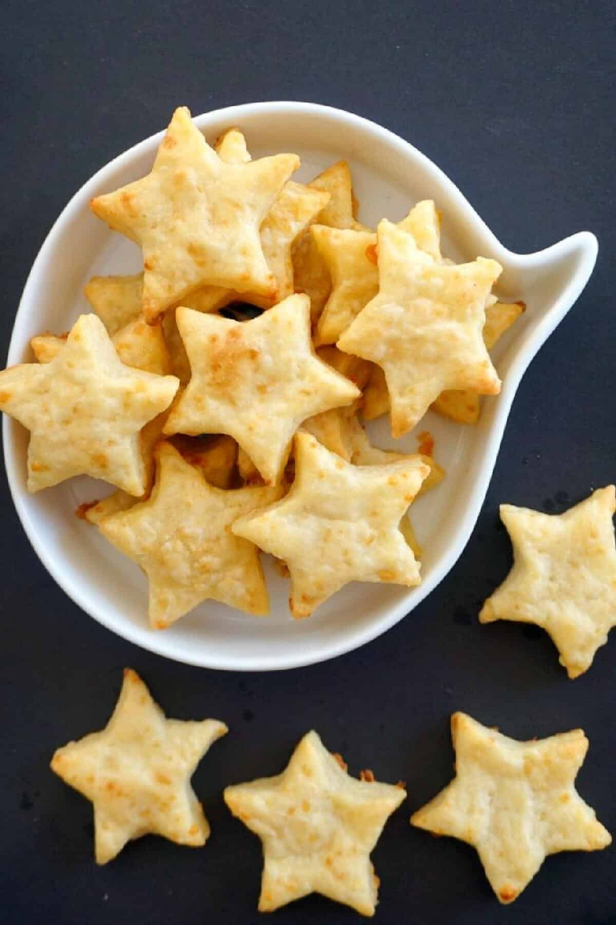 Overhead shoot of a white bowl with star shaped crackers and 4 crackers on the outside of the bowl.