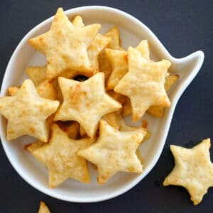 Overhead shoot of a white bowl with star-shaped crackers with one cracker on the outside of the bowl