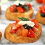 2 bruschetta slices topped with chopped tomatoes, olives and parmesan