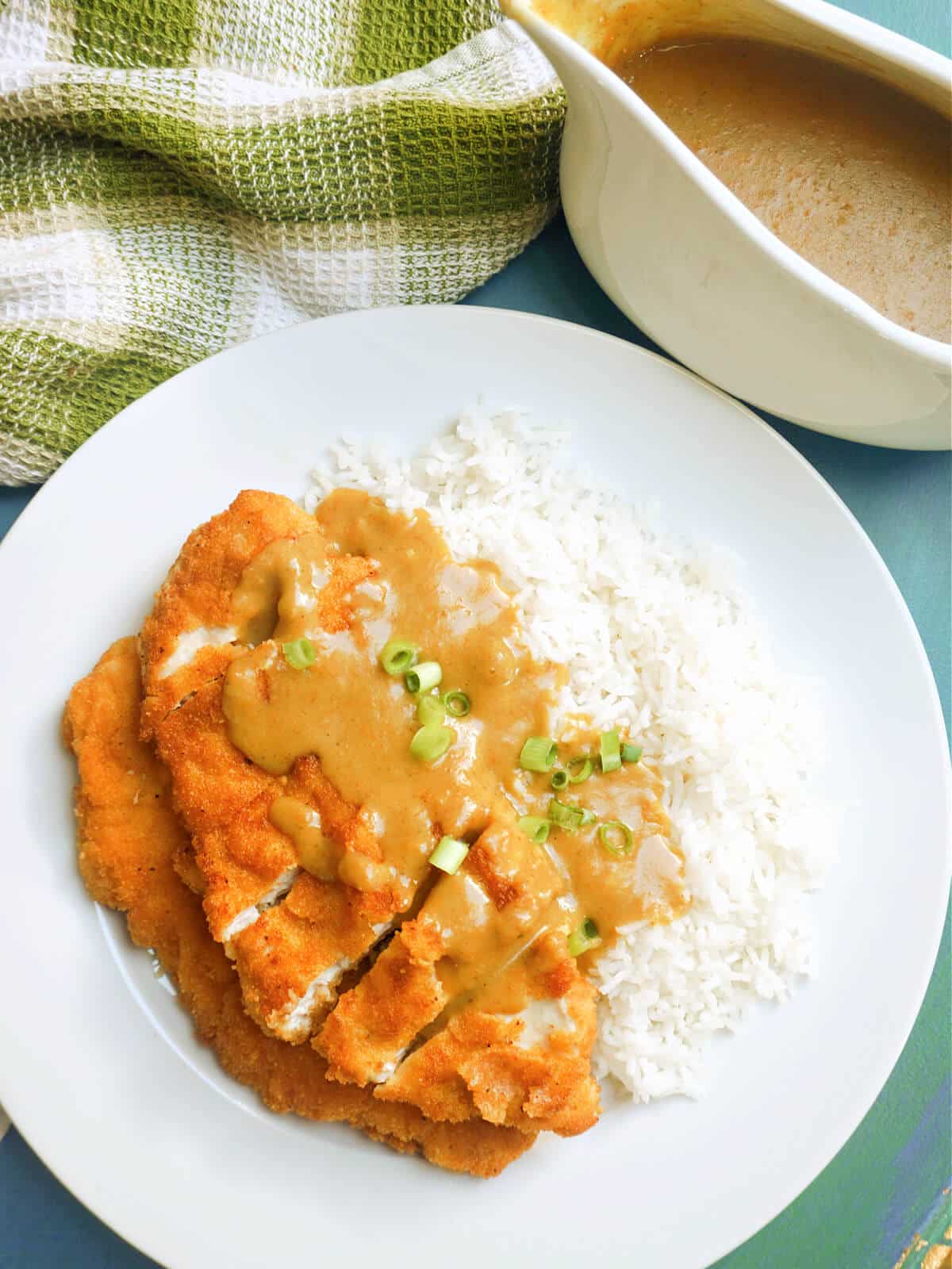 Overhead shoot of a plate with rice topped with a chicken cutlet in a katsu sauce.