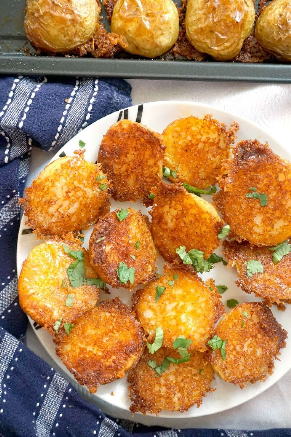 A white plate with parmesan crusted roast potatoes.