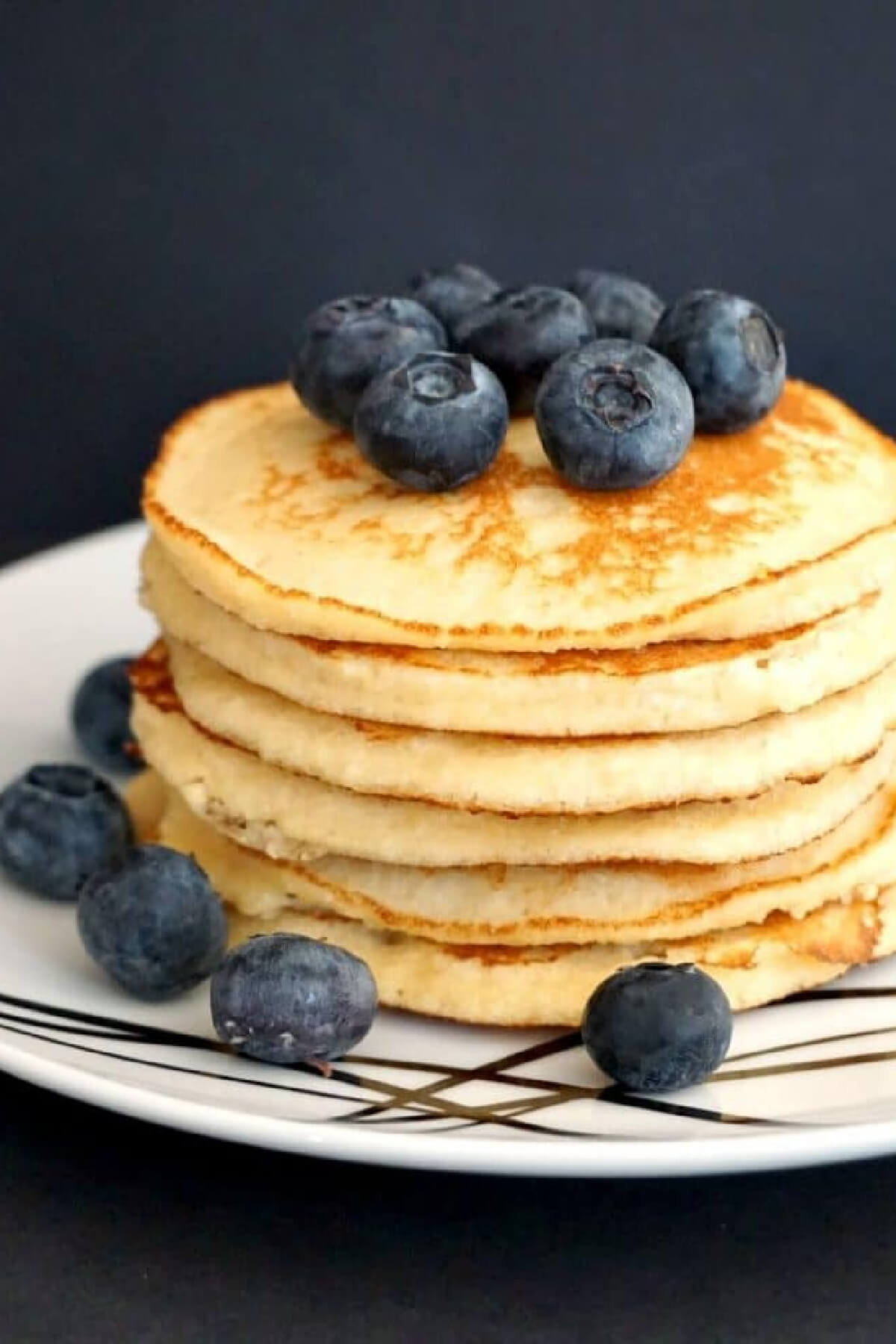 A pile of pancakes topped with blueberries.