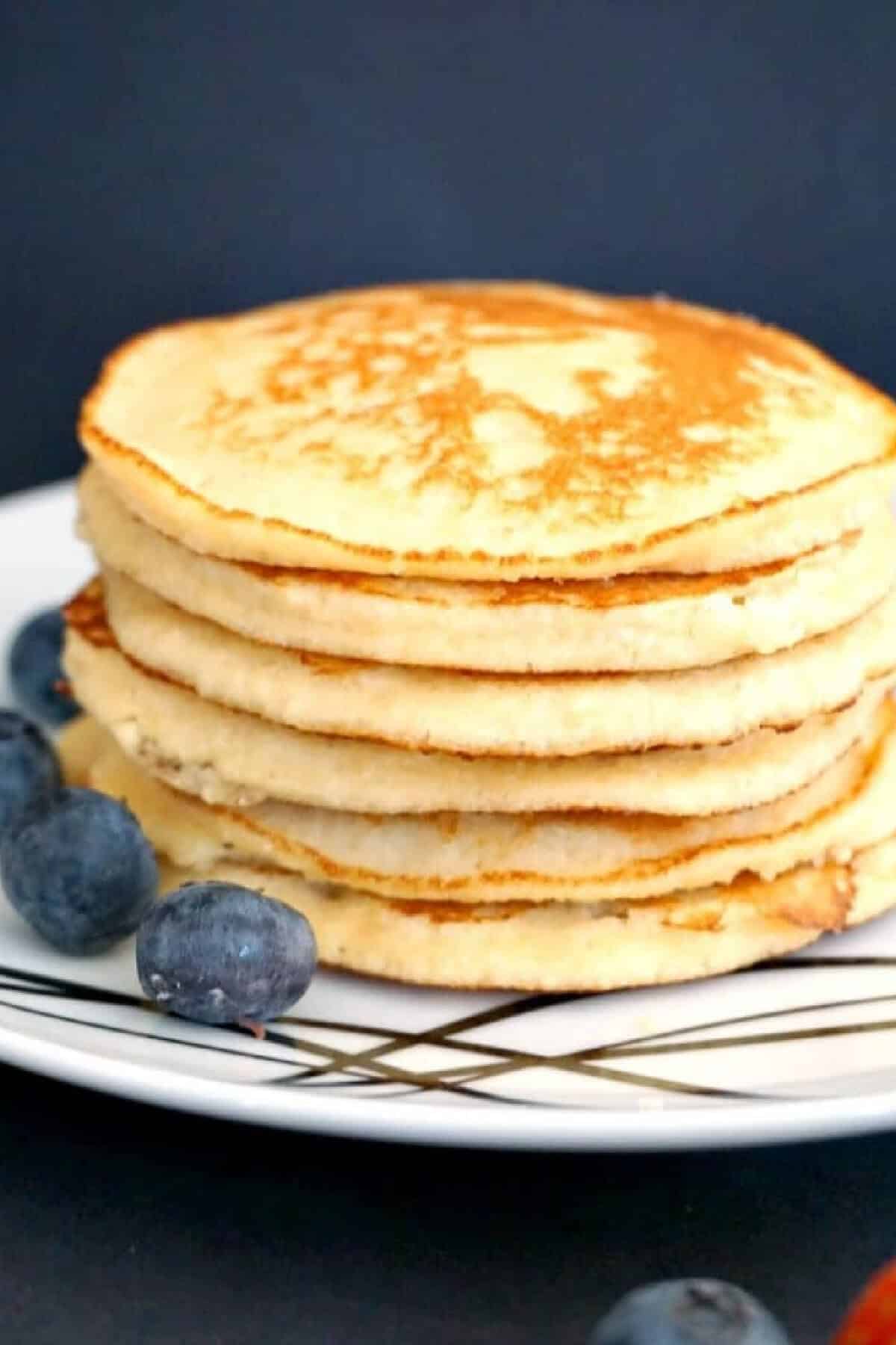 A pile of almonds on a white plate with blueberries around.