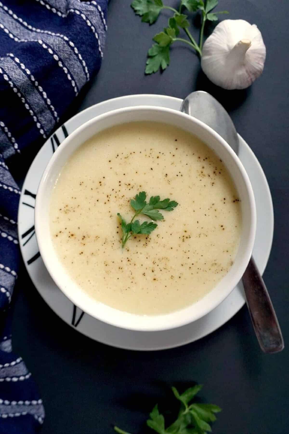 Overhead shoot of a white bowl with cream of garlic soup.
