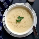 A white bowl with cream of garlic soup