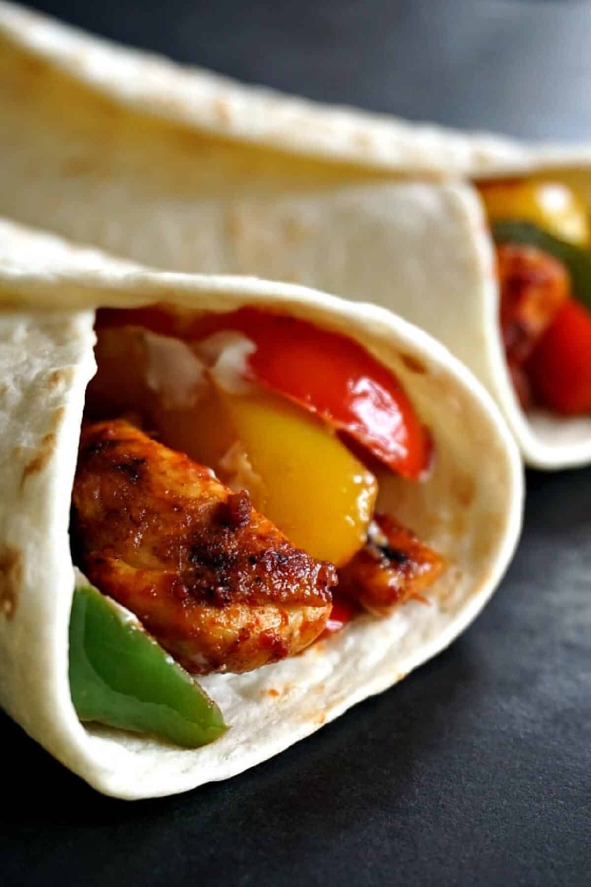 Close-up shoot of a tortilla wrap with chicken and peppers.
