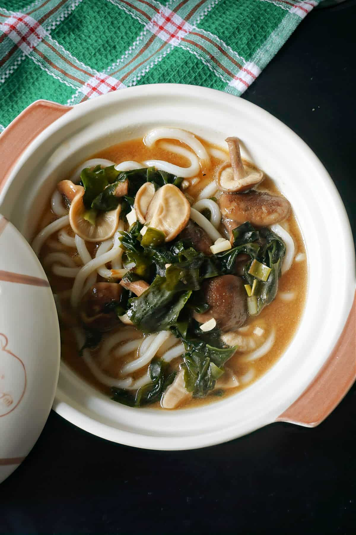 A white bowl with miso udon noodle soup.