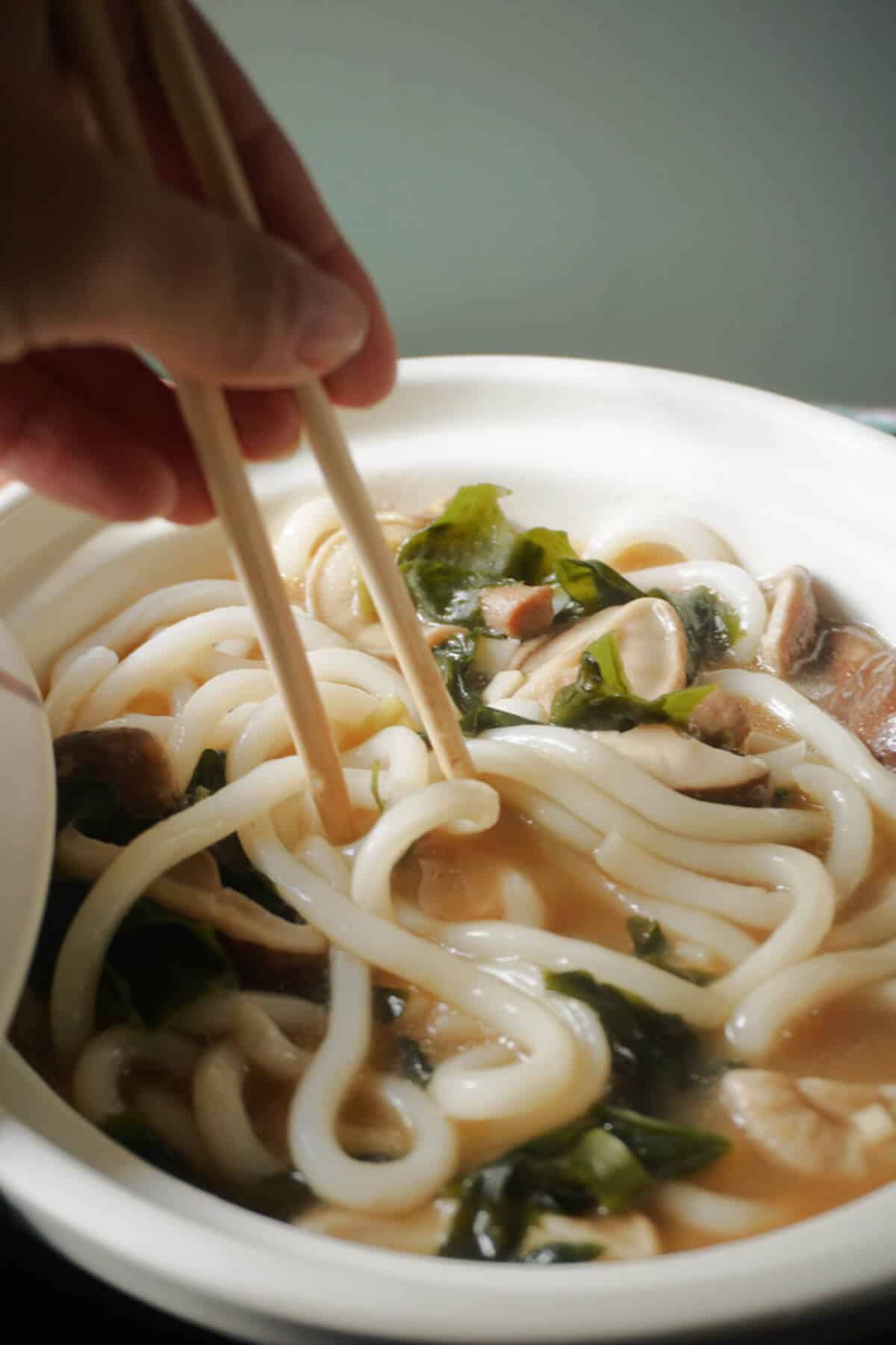 Close-up shoot of a white bowl with miso udon noodle soup.