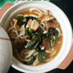 A white bowl with miso udon noodle soup.