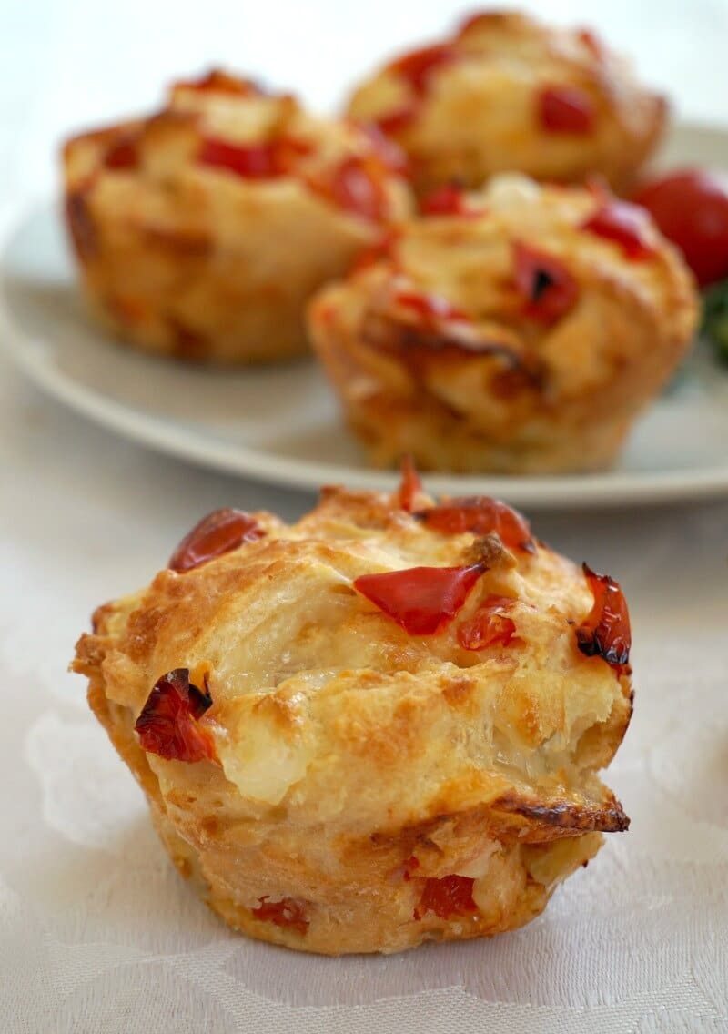 A savoury muffin with a plate of other muffins in the background.