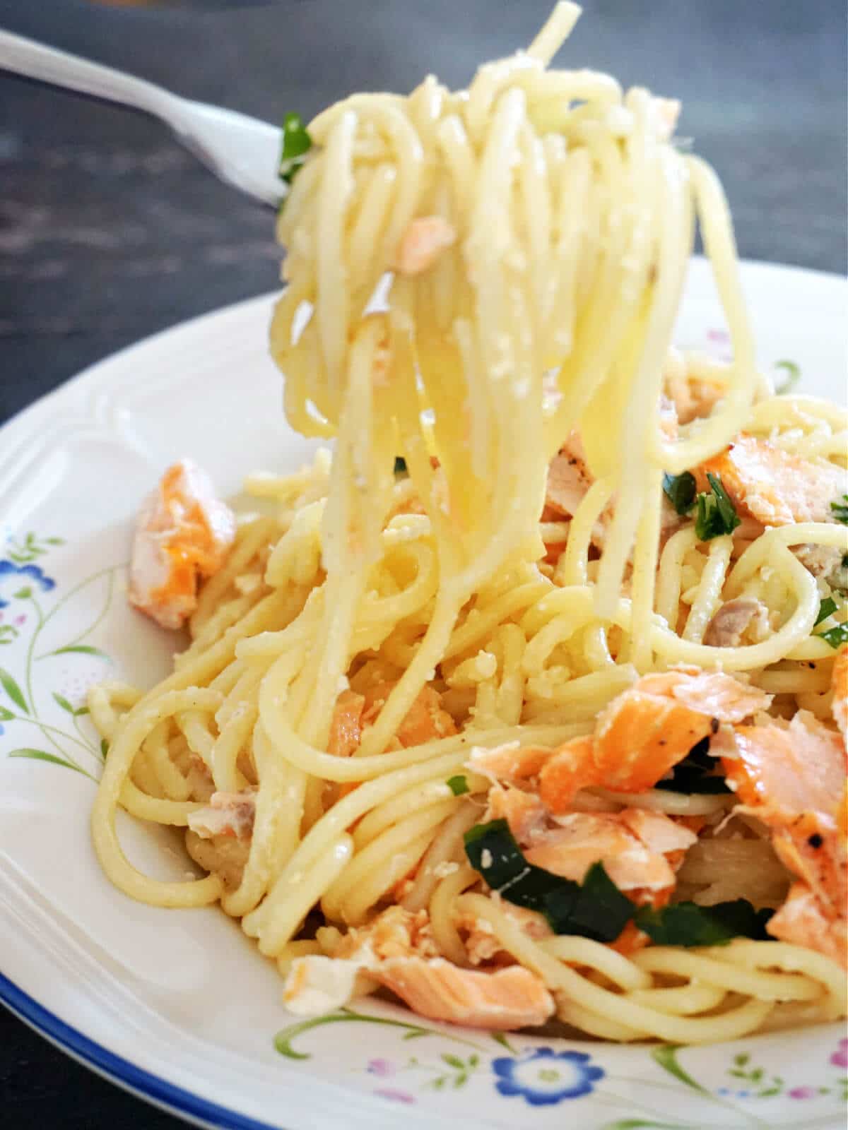 Pasta carbonara with salmon on a white plate.