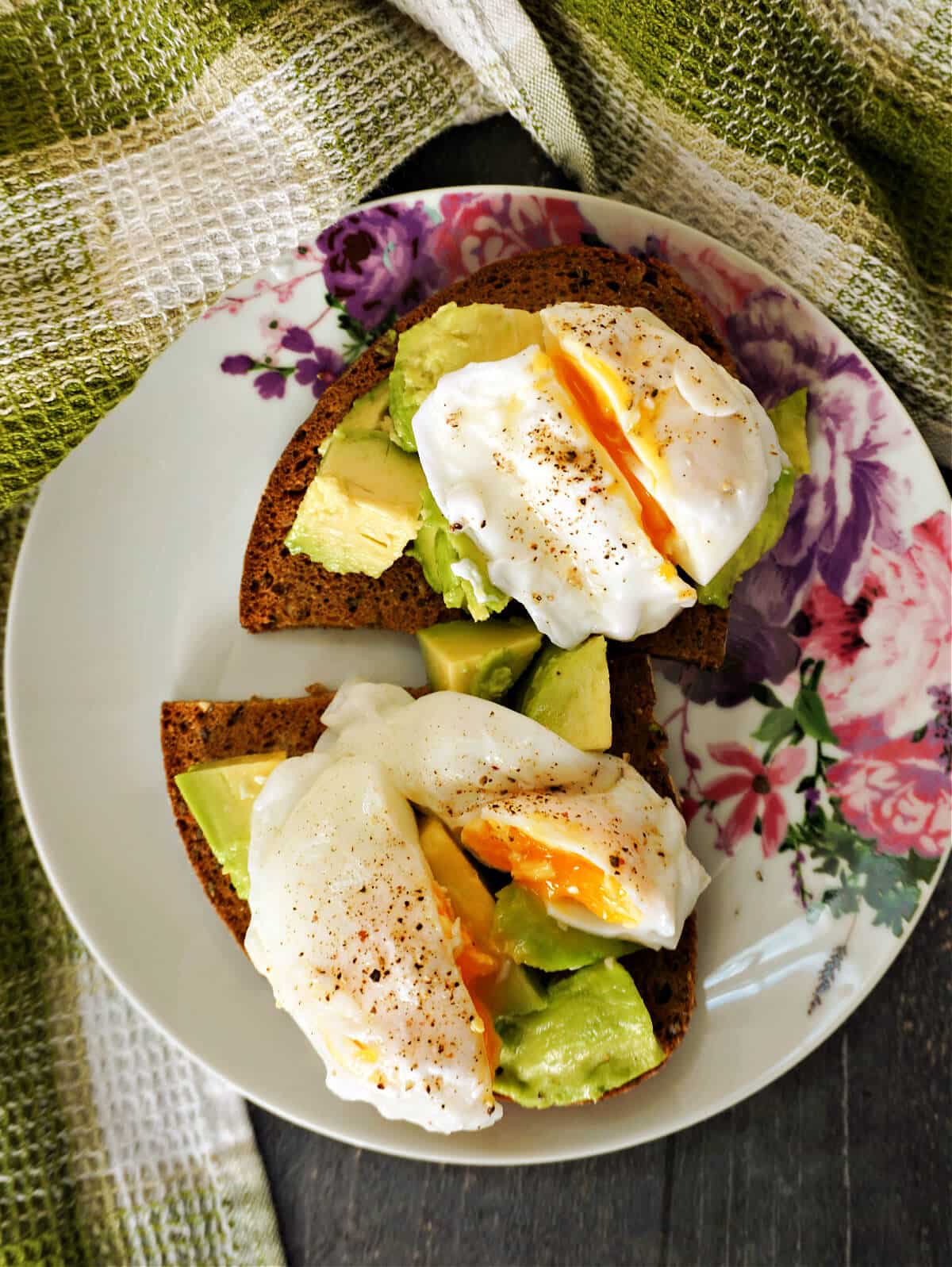 Overhead shoot of a plate with 2 slices of bread with avocado and poached eggs on top.