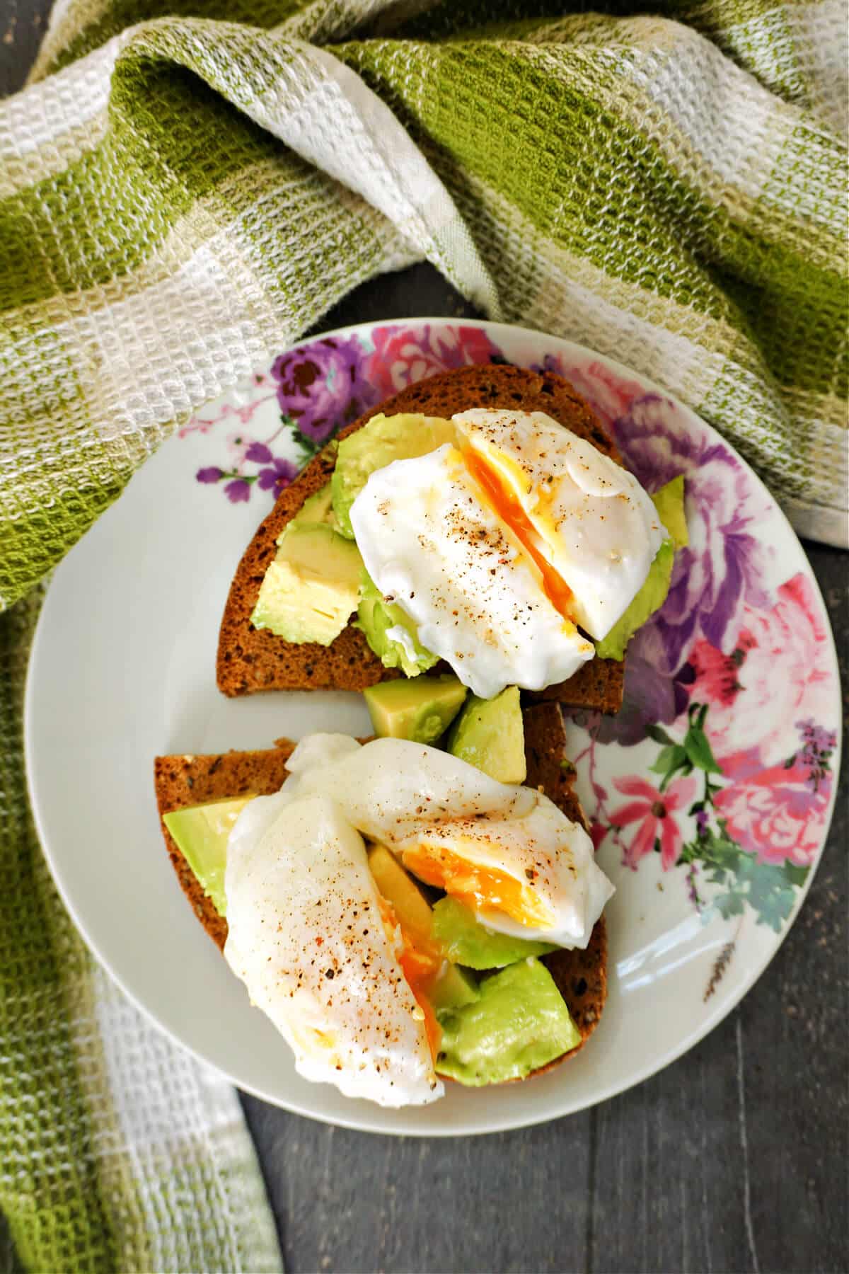 Overhead shoot of a white plate with 2 slices on toast with avocado and poached eggs