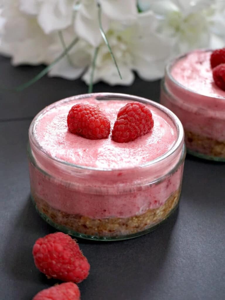 A ramekin with raspberry mousse topped with 2 raspberries