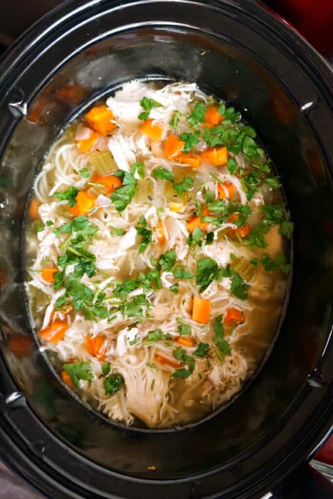 A crockpot with chicken and noodle soup