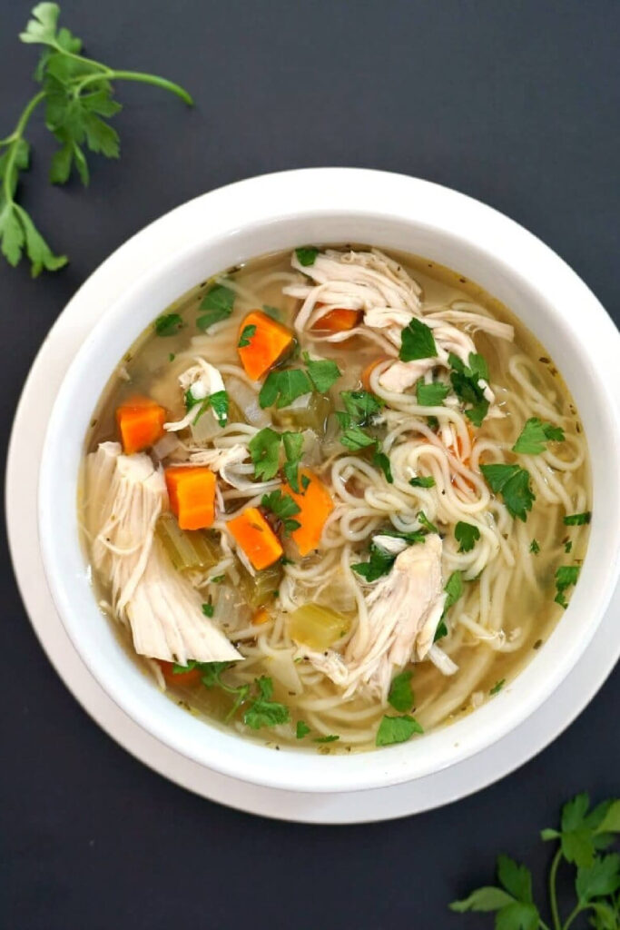 Overhead shoot of a white bowl with chicken and noodle soup