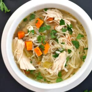 Overhead shoot of a white bowl with chicken noodle soup
