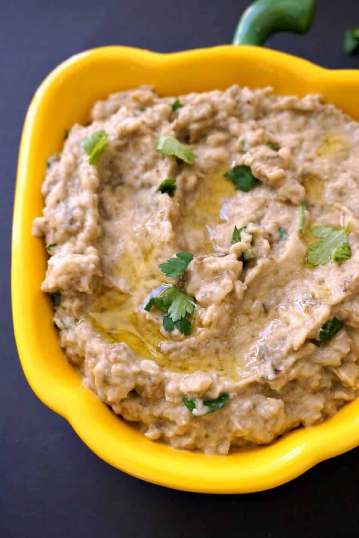 A yellow bowl with aubergine dip.