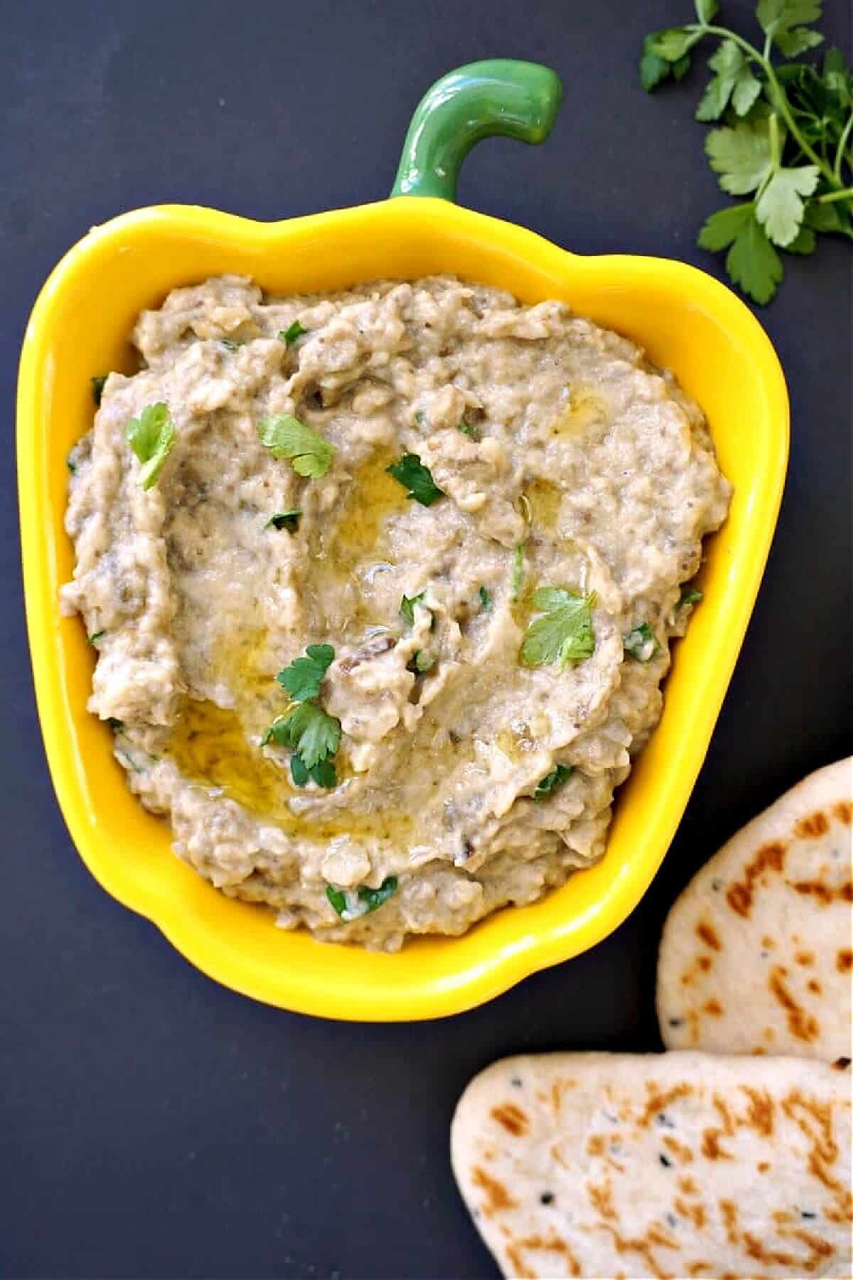 Overhead shoot of a yellow pepper-shaped bowl with aubergine dip.