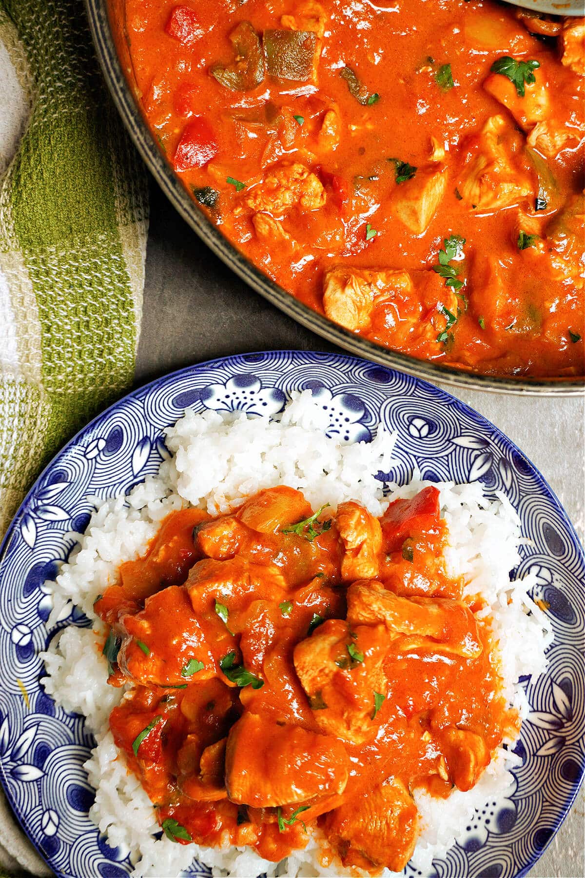 Overhead shoot of a blue plate with goulash on a rice bed and a pot with more goulash.