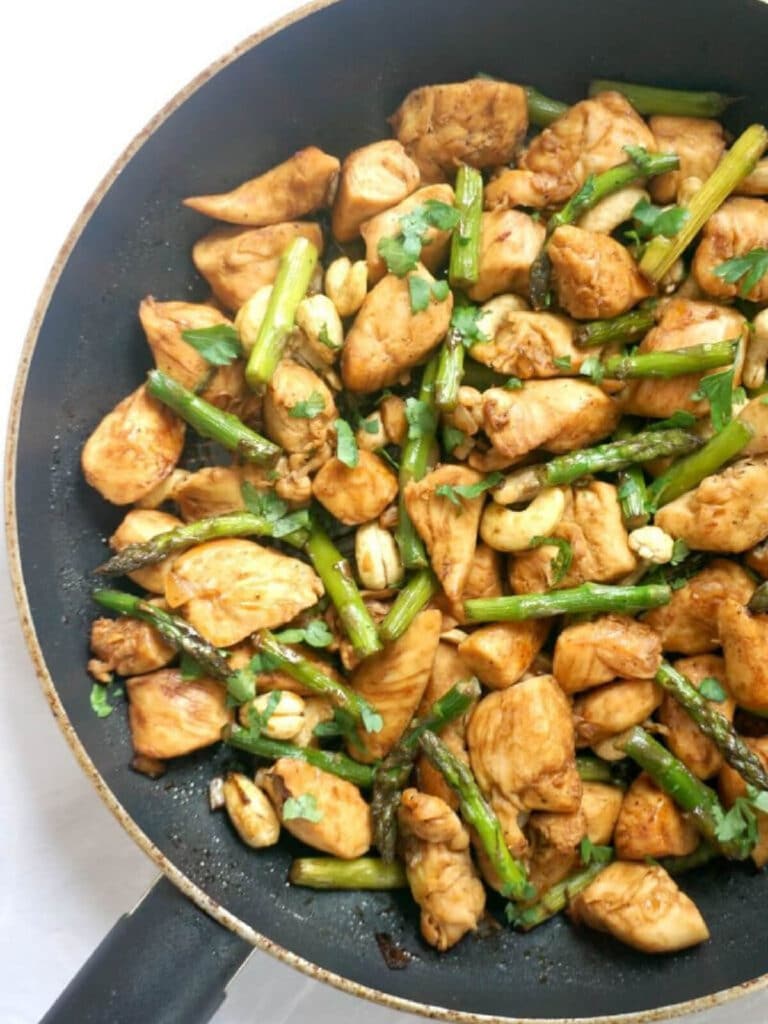 A pan with chicken pieces and asparagus