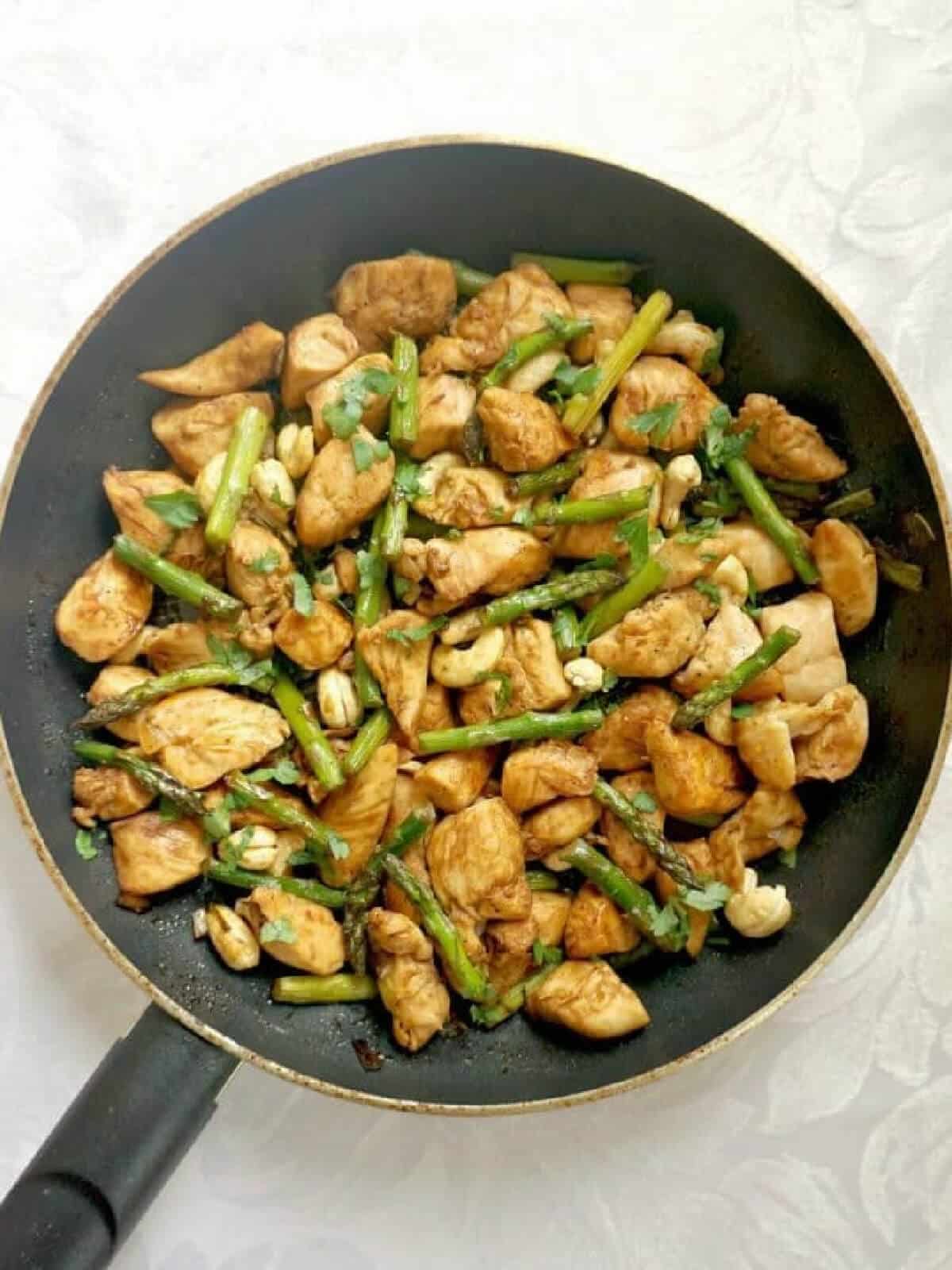 Overhead shoot of a pan with chicken and asparagus stir fry.