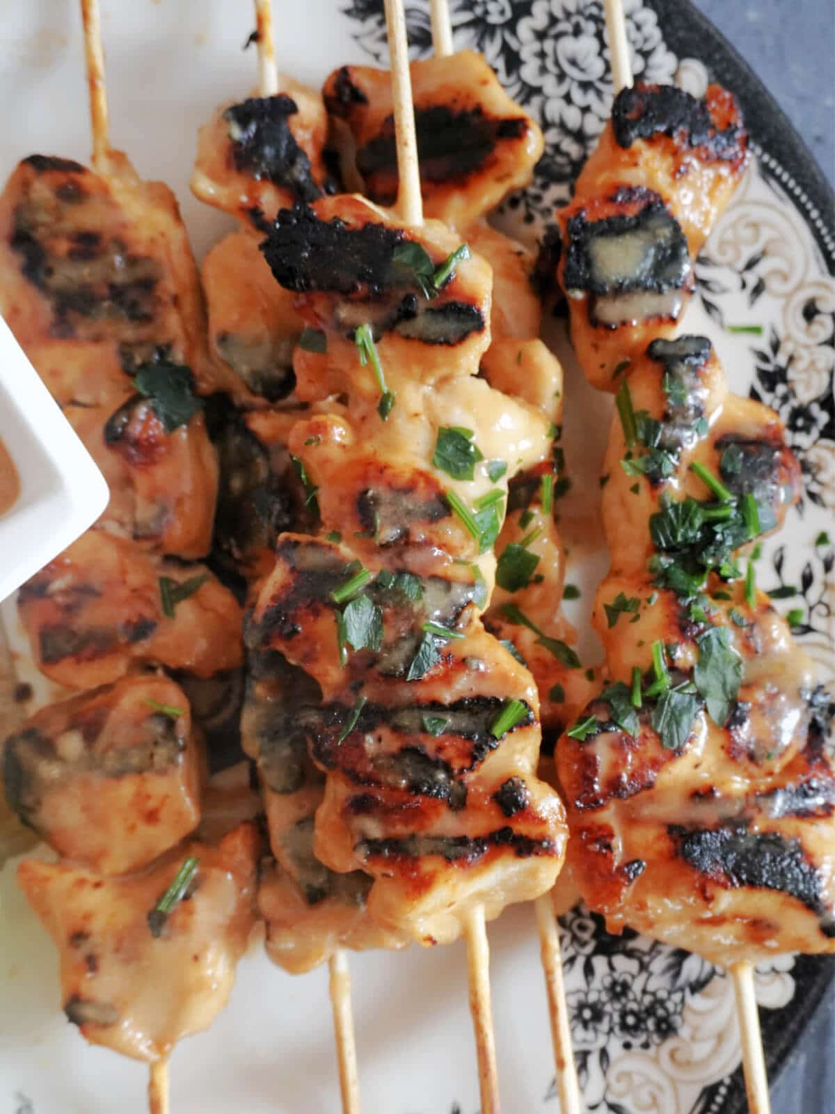 Close-up shot of chicken satay skewers on a plate.