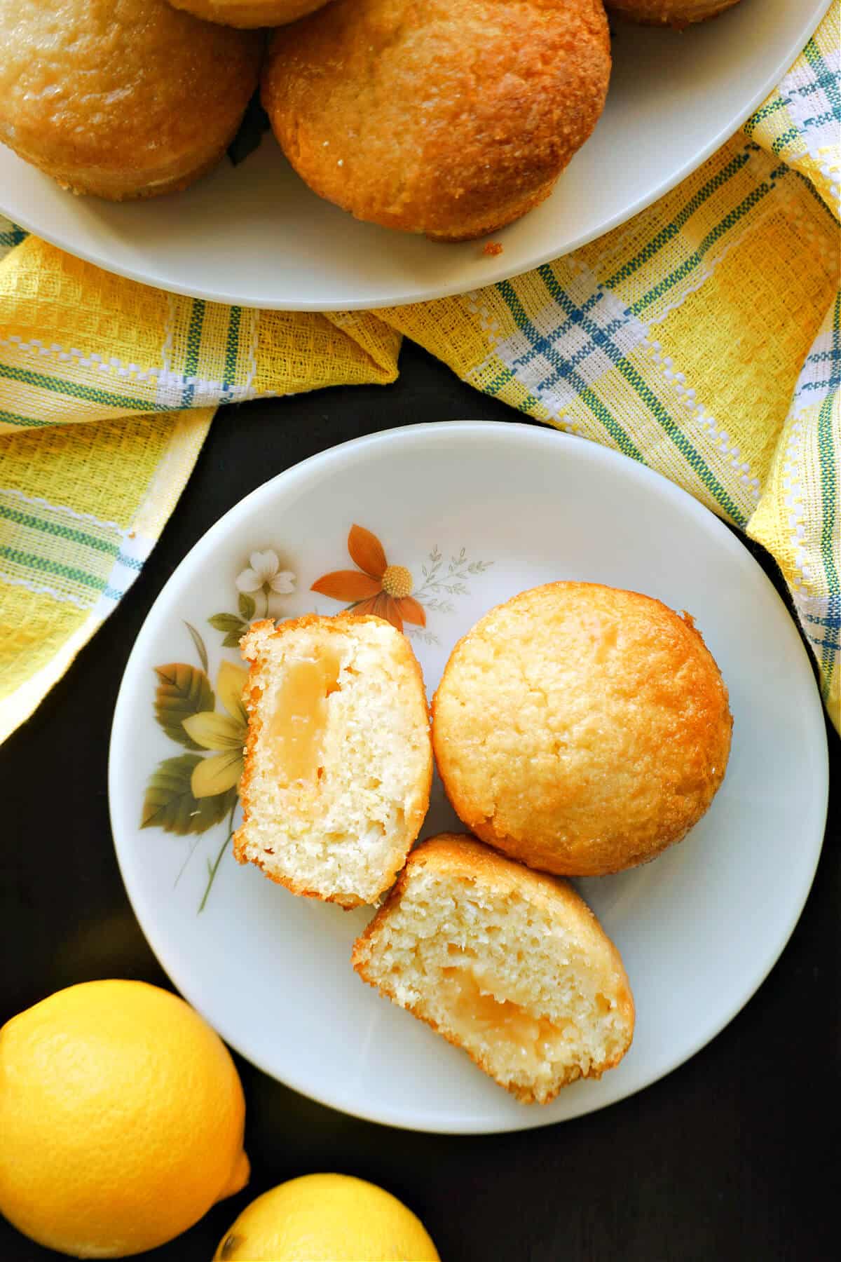 Overhead shoot of a white plate with 2 halves of a lemon muffin and a whole muffin.