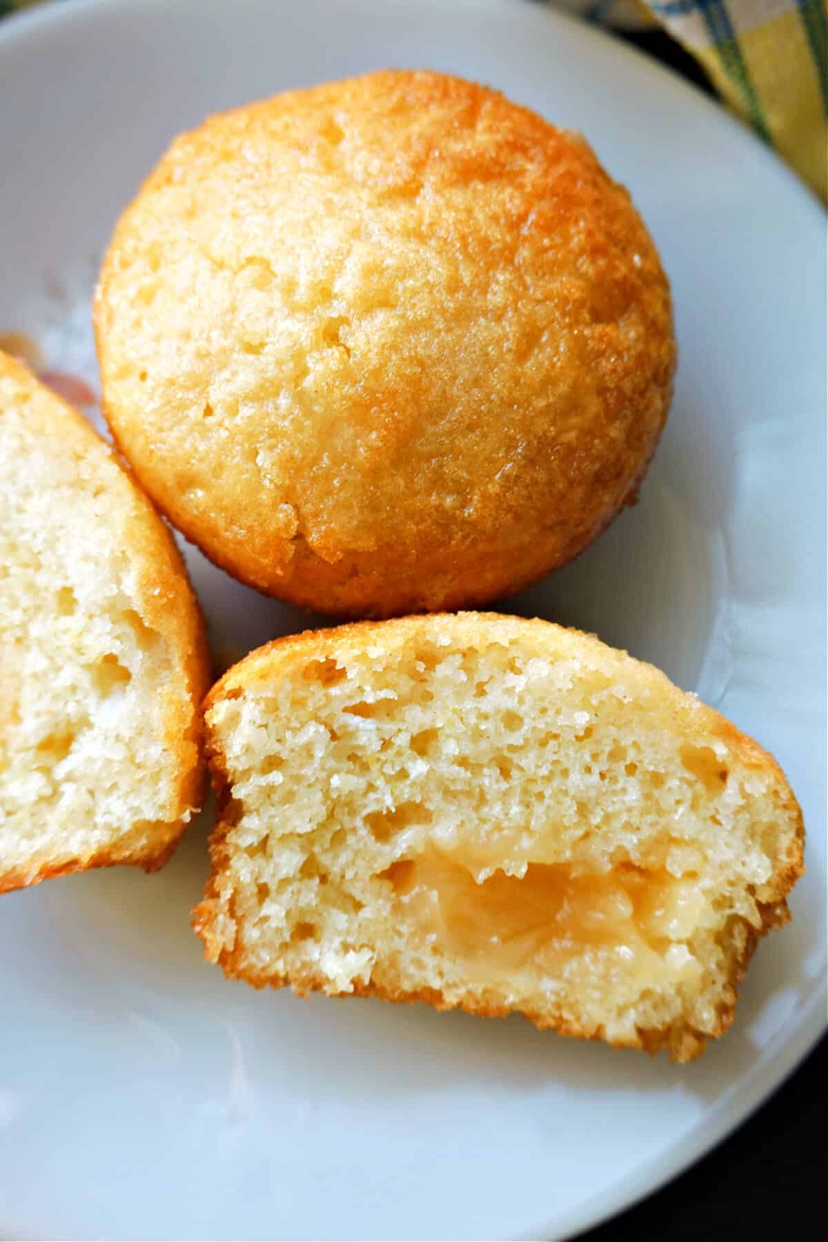 2 halves of a lemon muffin and a whole muffin on a plate.