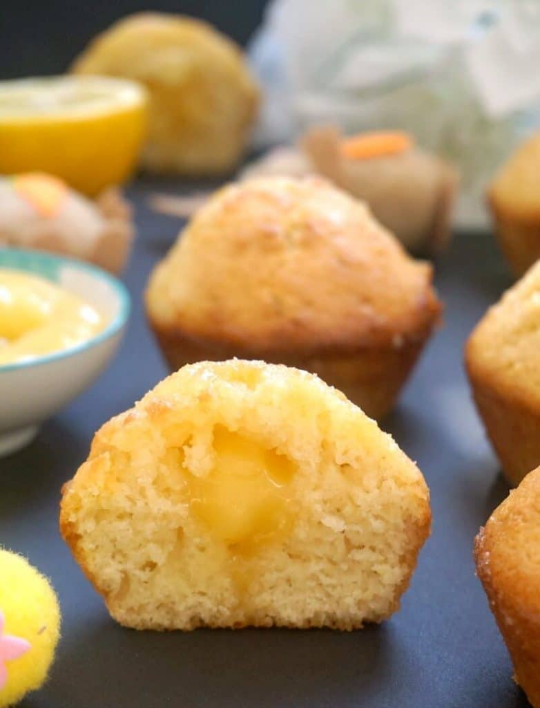 Half of a lemon drizzle muffin filled with lemon curd, with other lemon muffins around it