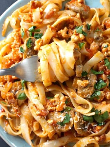 Overhead shoot of a light blue plate with tagliatelle with meat sauce