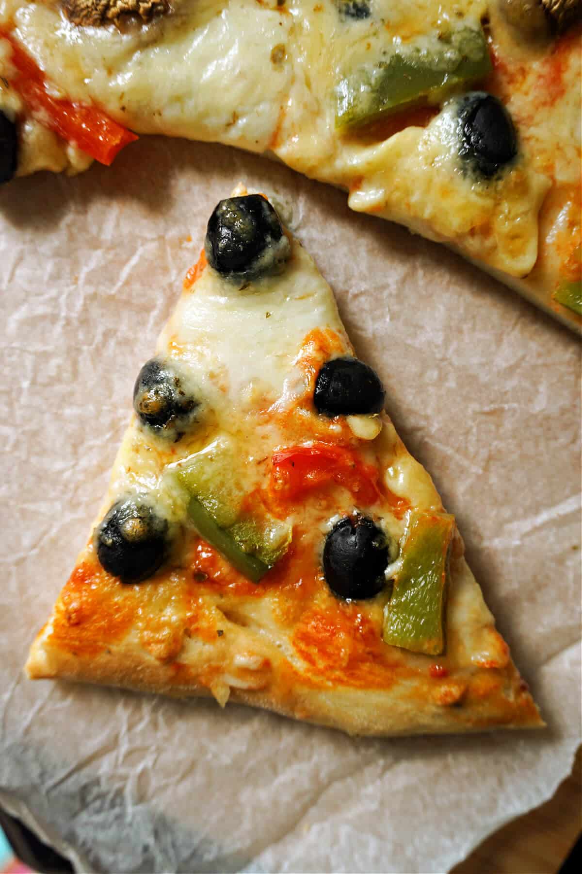 A slice of veggie pizza on a tray lined with non-stick paper.